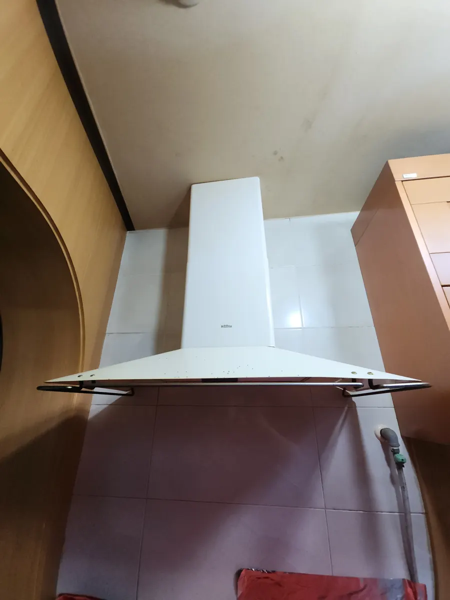 타일 벽 앞에 굴뚝형 흰색 후드가 천장까지 이어져 설치된 주방