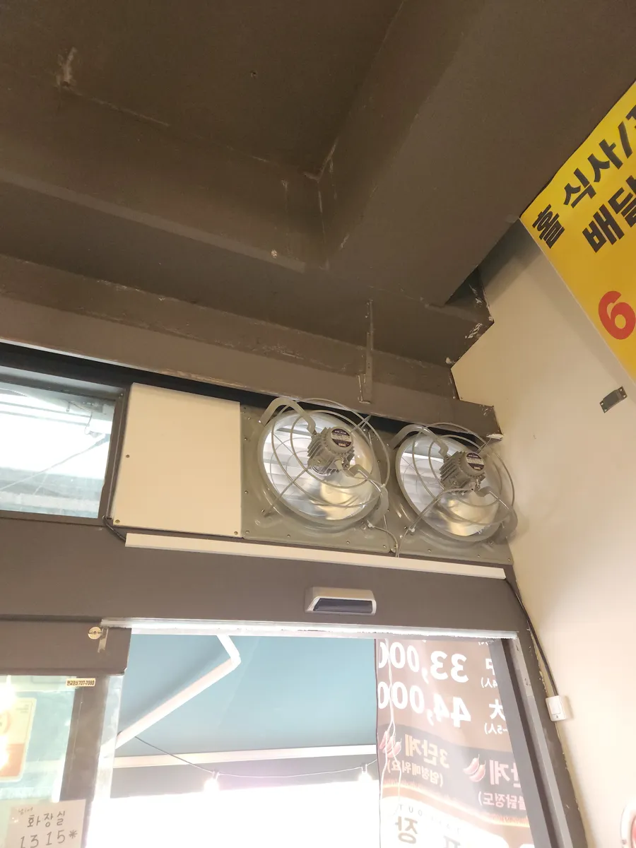 출입구 상부에 환풍기 두 대를 나란히 설치한 가게 내부