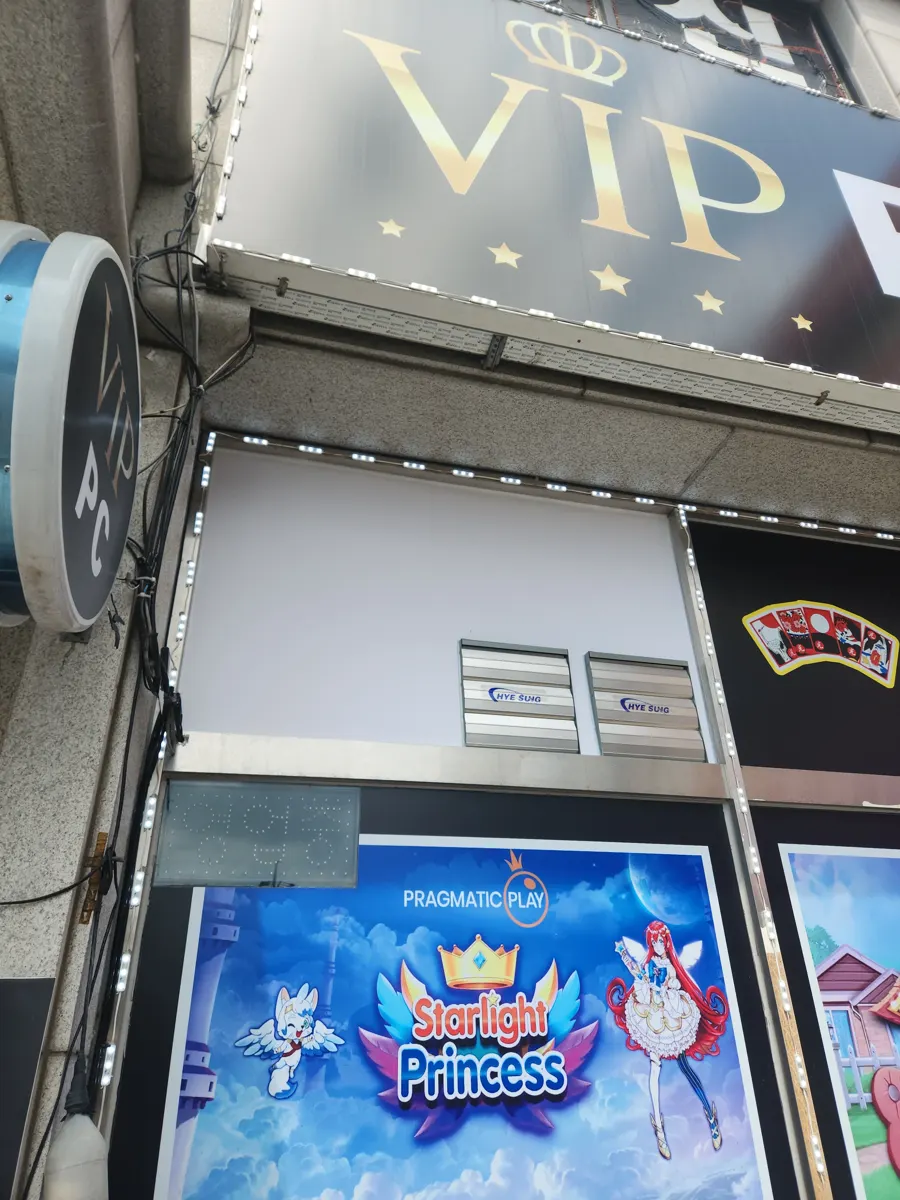 상가 간판 아래 흰 외벽 패널에 설치된 루버형 환풍구 두 개
