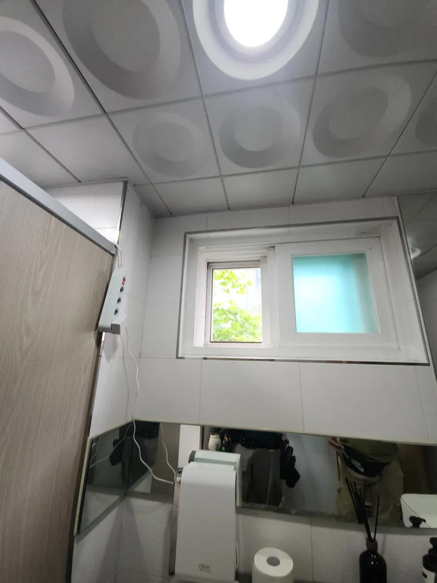 흰 타일 벽과 작은 창, 천장 조명이 보이는 화장실 내부 점검 장면