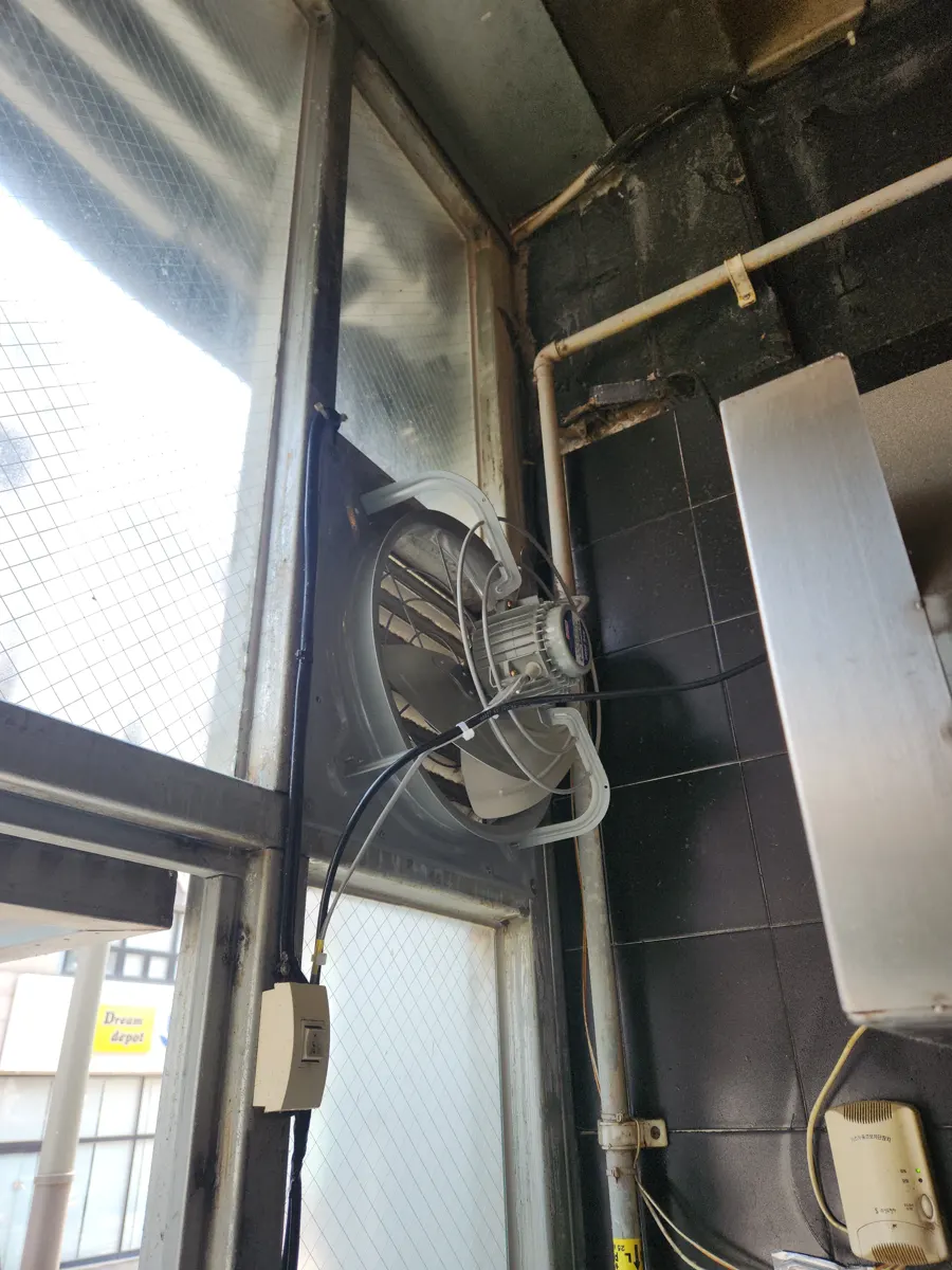 창가 벽에 고정된 벽부 환풍기와 아래로 내려간 전선