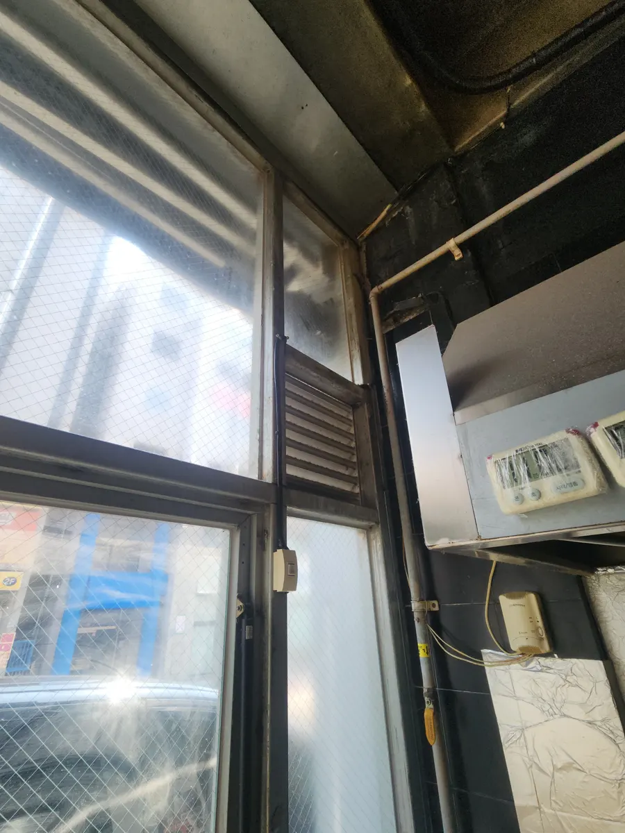 창 옆 벽면 위쪽에 설치된 덕트와 환풍구 주변