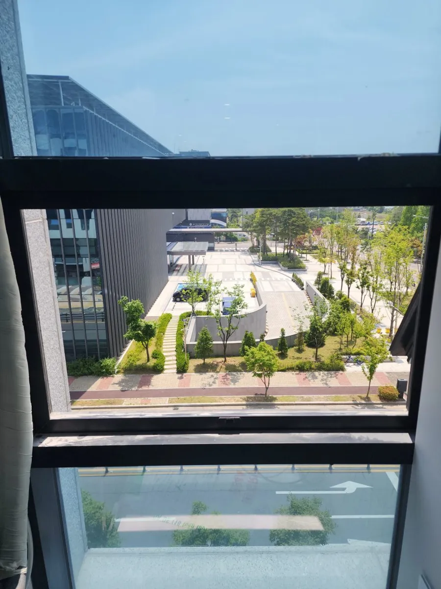 고층 창문 너머로 주변 건물과 도로가 보이는 환기 설치 현장