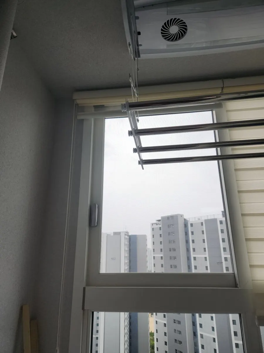 베란다 창가 모서리에 건조대와 블라인드가 있는 환기구 주변 공간