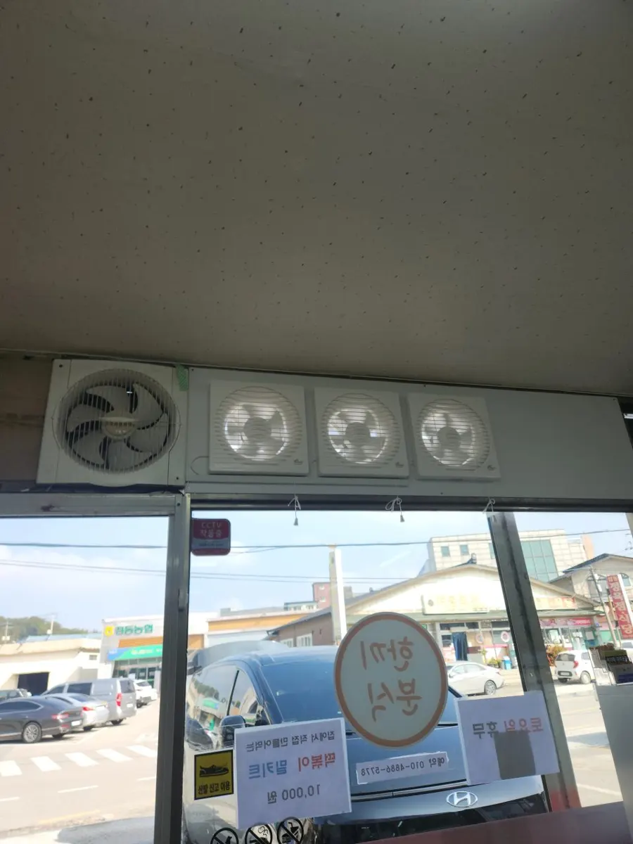 상가 매장 창 상단에 한 줄로 설치된 환풍기 네 대와 창밖 도로 풍경