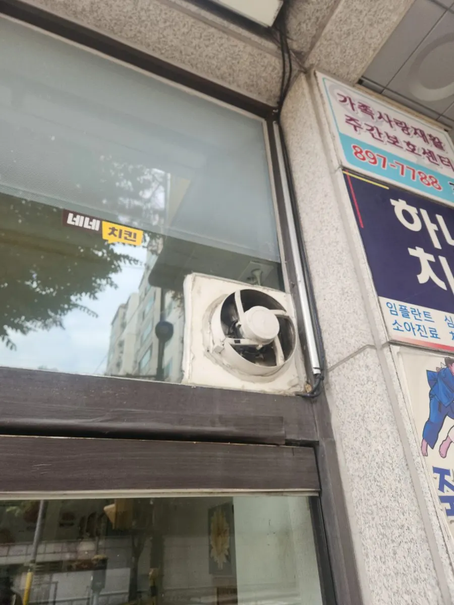 철거 직전 날개와 본체에 때가 낀 구형 흰색 환풍기가 창 아래에 붙은 모습
