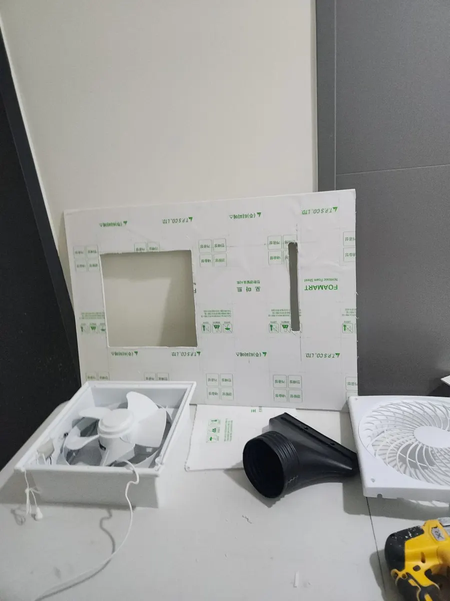 상자에서 꺼낸 새 환풍기와 구멍을 뚫어 만든 흰색 판재