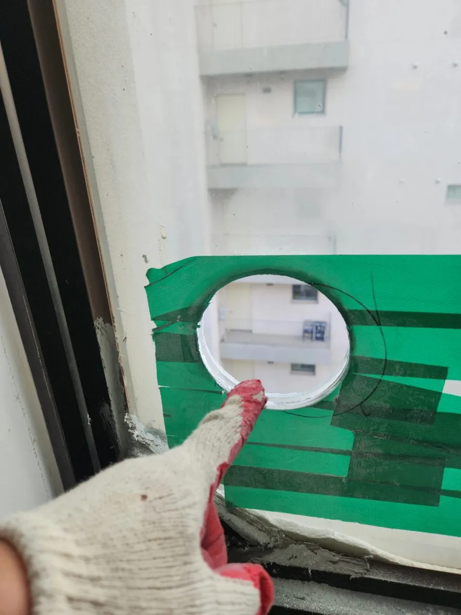 유리에 환풍기용 원형 구멍을 뚫은 직후 가루가 남아 있는 작업 장면